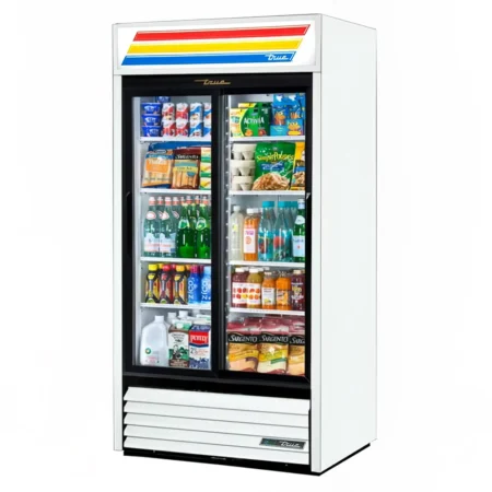 A white True brand commercial two-section glass door merchandiser refrigerator with sliding doors, filled with various beverages, dairy products, and snacks, featuring a lighted sign on top.