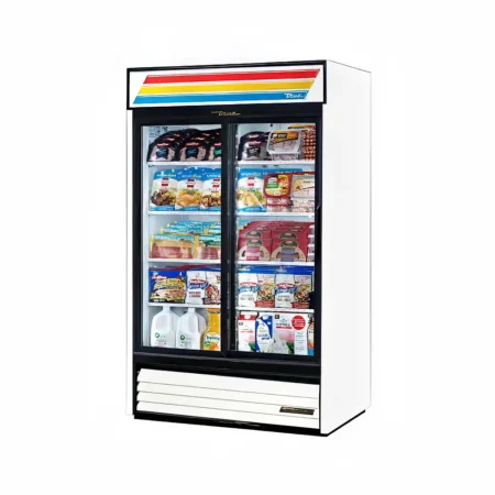 A white commercial double-door refrigerator by True with sliding glass doors, fully stocked with packaged meats, cheese, juice, and milk cartons, featuring a colorful striped brand sign on top.