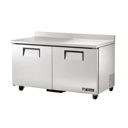An angled view of a wide 60-inch True stainless steel two-door worktop freezer featuring recessed handles, a built-in rear backsplash, and side ventilation on locking swivel casters.